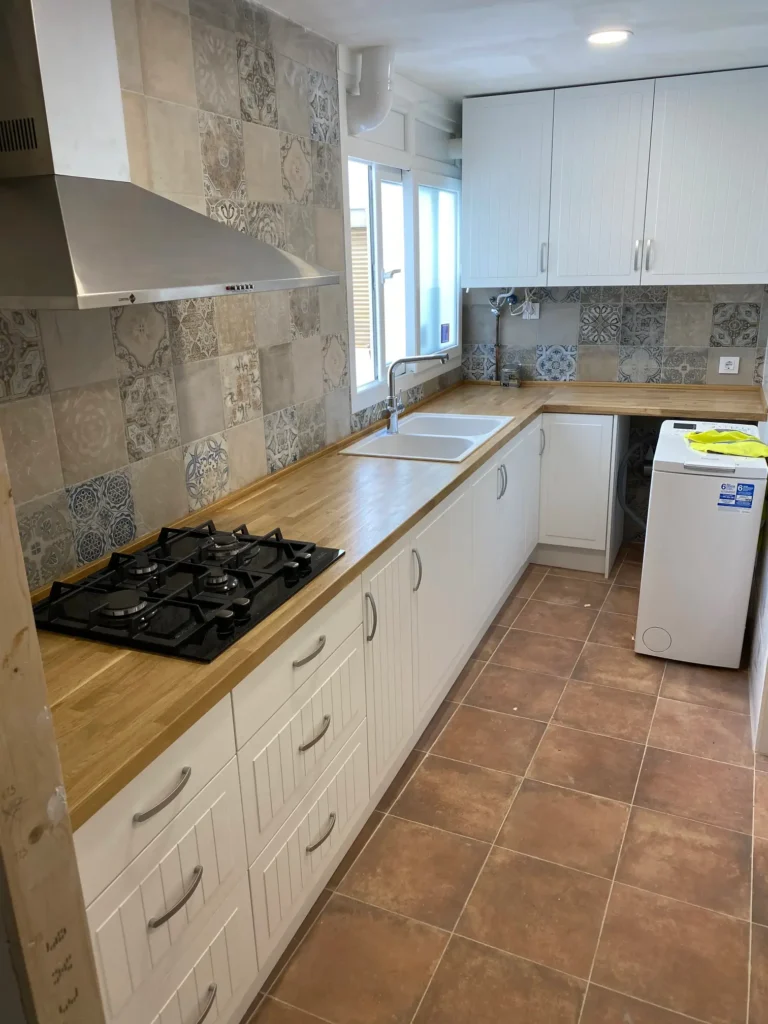 Cocina con puertas claras nuevas y encimera de madera en Valencia